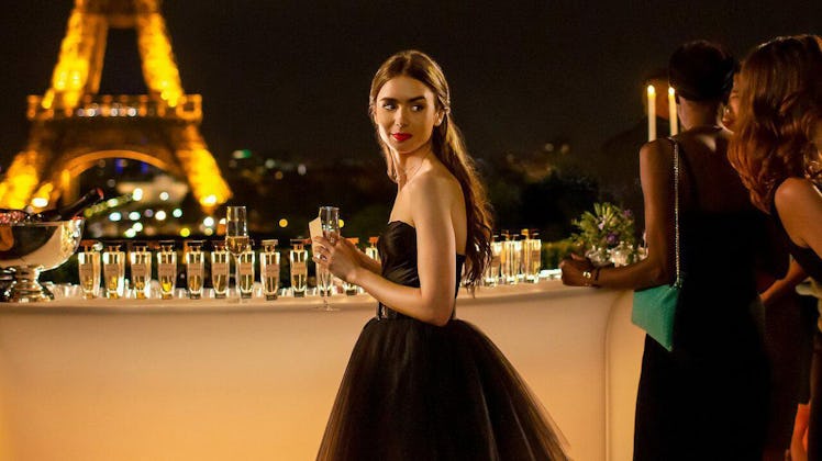 Emily (Lilly Collins) from 'Emily in Paris' stands by the bar at a party, wearing a black gown, near...