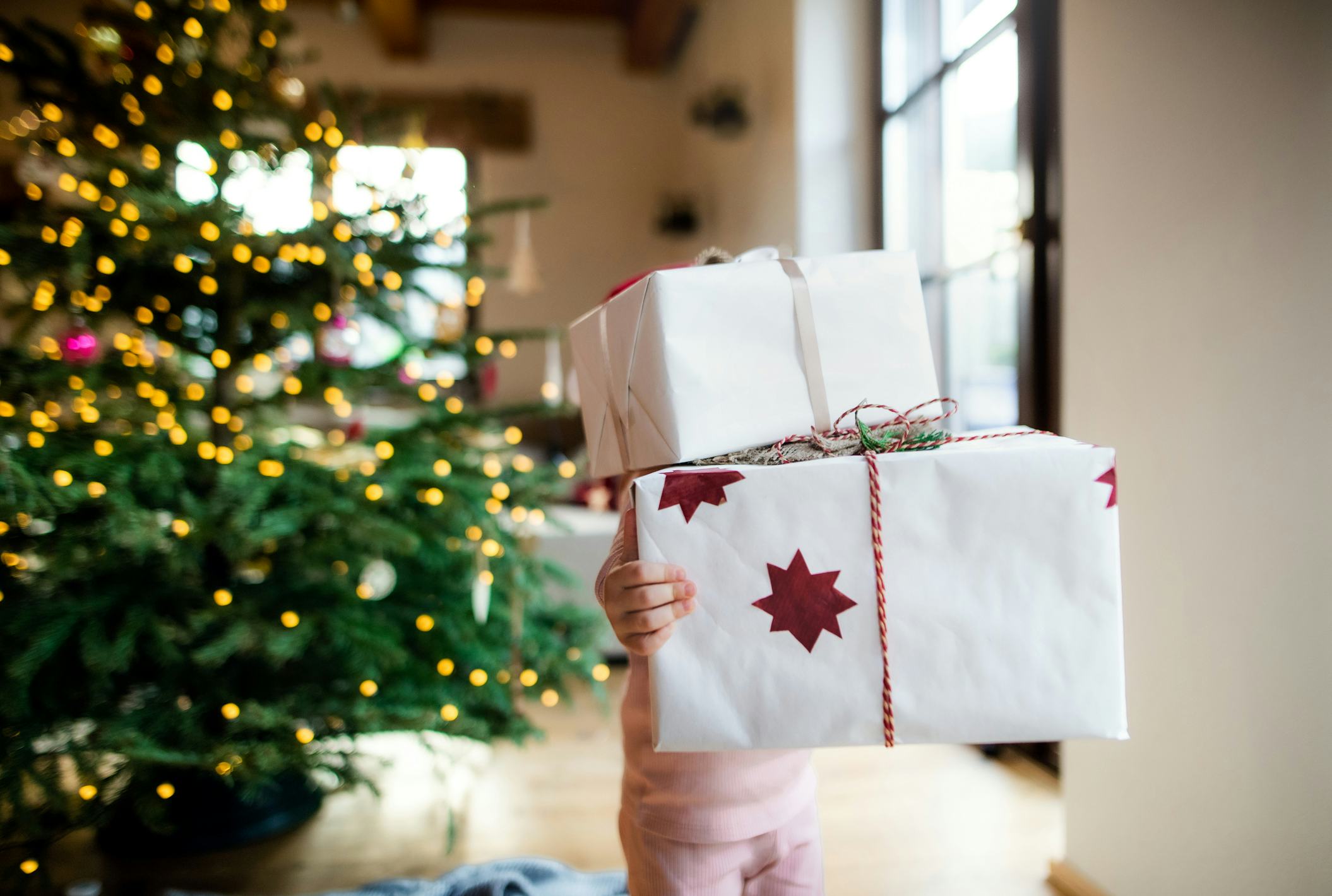 child holding a stack of christmas presents