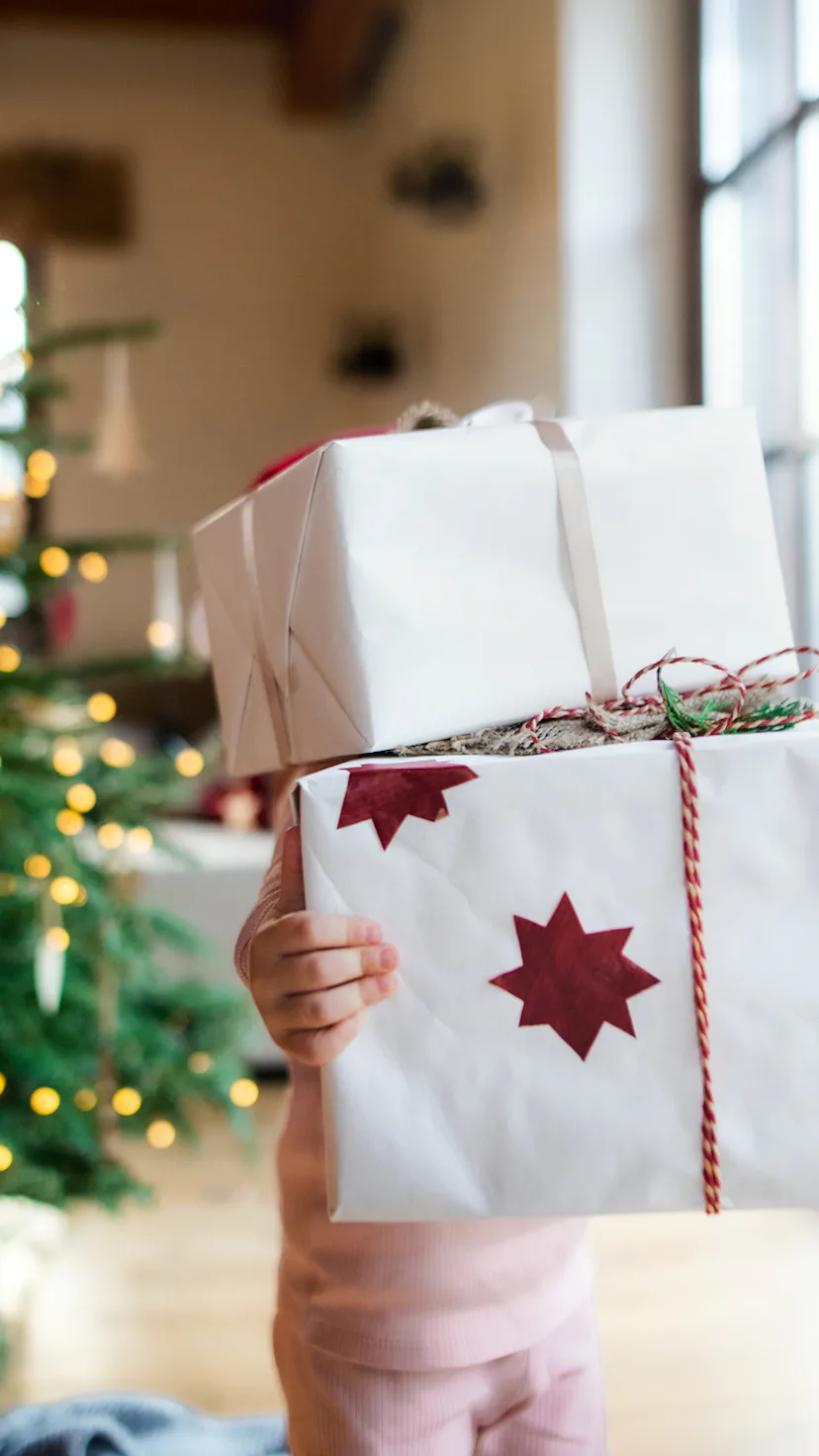 child holding a stack of christmas presents