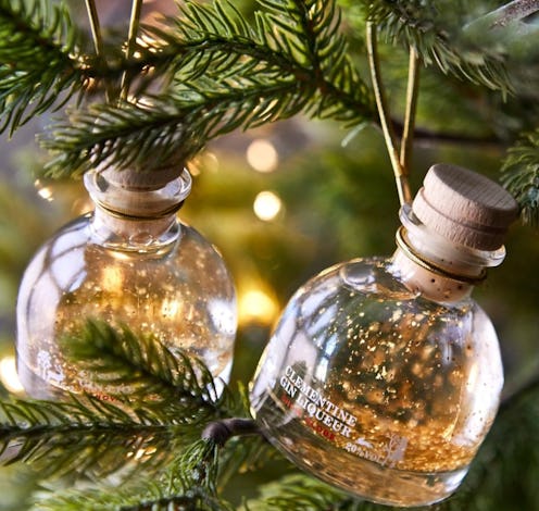 Small wood-stoppered gin bottles filled with a clear liquid and flakes of gold leaf nestled in chris...