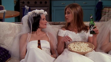 Monica (Courteney Cox) and Rachel (Jennifer Aniston) chill on the couch in wedding dresses, eating p...
