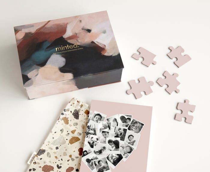 Minted box, photo, bag, and puzzle pieces scattered on a white table