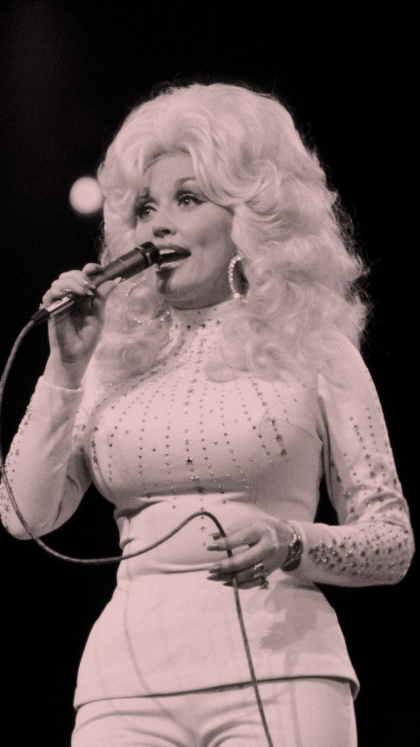 Dolly Parton on stage with big blonde hair and pink matching outfit in 1975.
