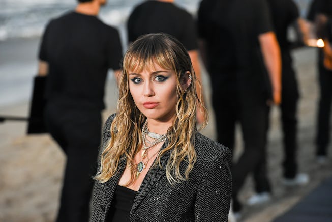 Miley Cyrus, with long hair and bangs, poses for a photo