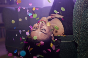 Young woman laying on sofa with confetti falling