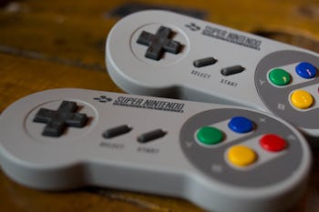 Two grey Nintendo Switch controllers placed next to each other on a wooden surface