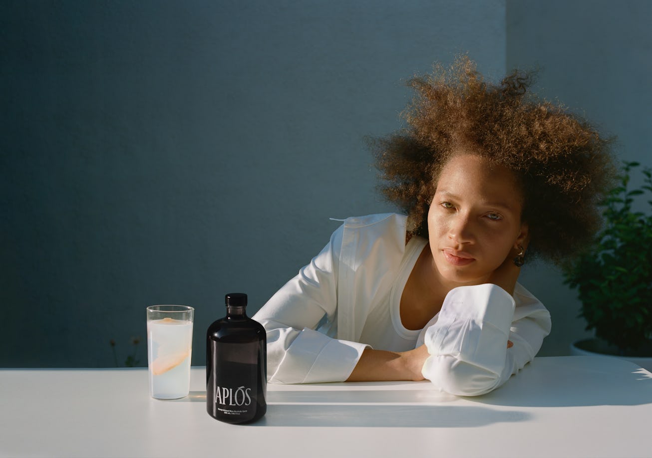 Model posing with bottle of Aplos beverage.