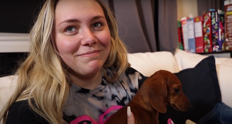 Kouvr from the Hype House sits on the couch with a puppy.