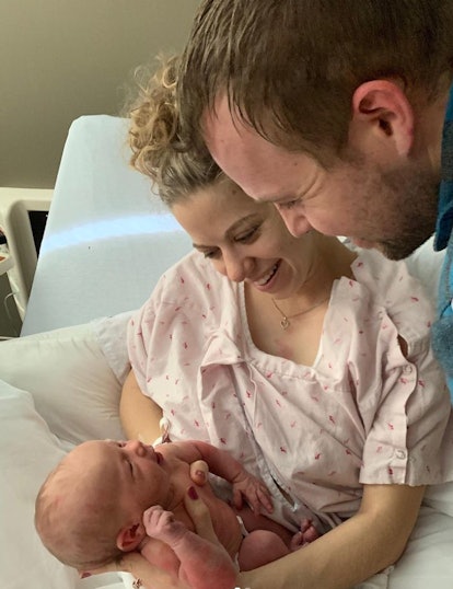 Abbie Duggar cradles her newborn daughter while sitting in a hospital bed as husband John Duggar loo...