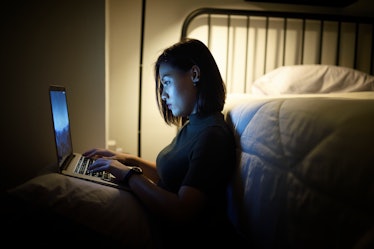 Woman work on her laptop at night near her bed