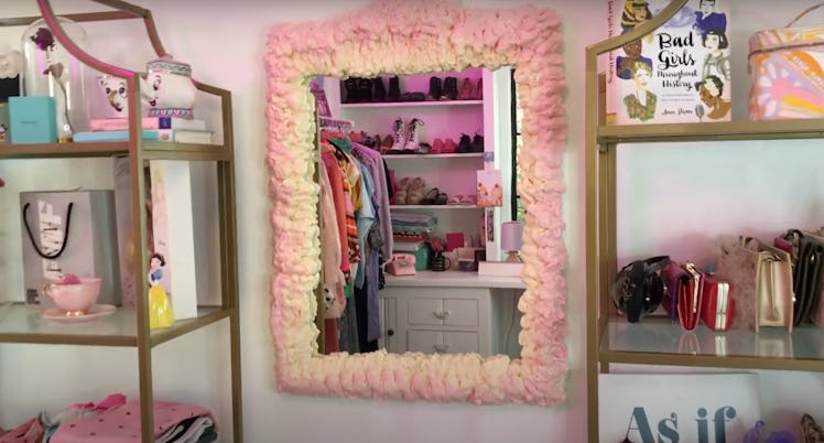 A DIY pink foam mirror sits on the wall next to filled shelves.