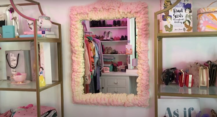 A DIY pink foam mirror sits on the wall next to filled shelves. 