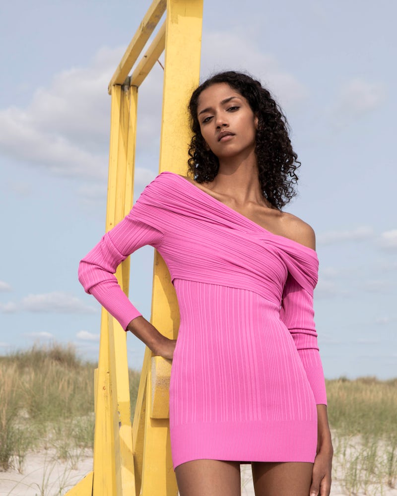 A model posing in a pink ribbed knit mini dress by Herve Leger