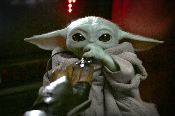 Baby Yoda, aka Grogu, nibbles on a necklace in the cockpit of the Razor Crest.