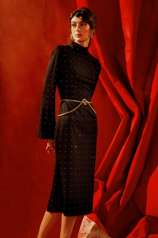 A model posing in a midi belted black dress embellished with rhinestones by Markarian