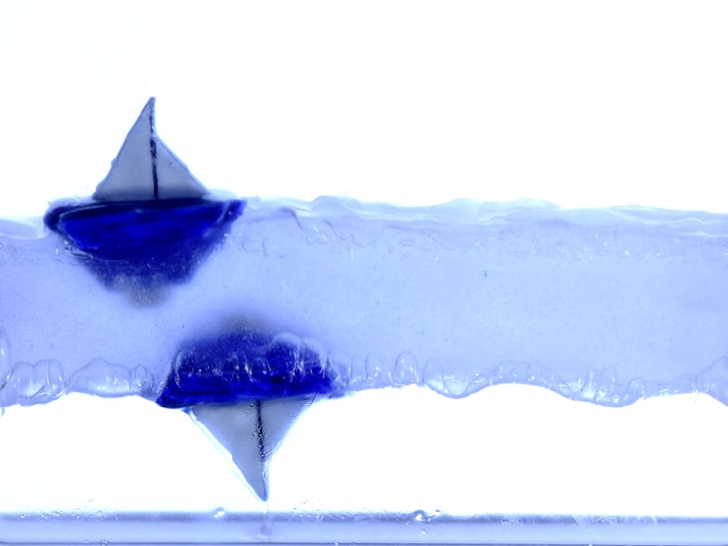 An illustration of a body of water and two blue sailboats on opposite sides of the water