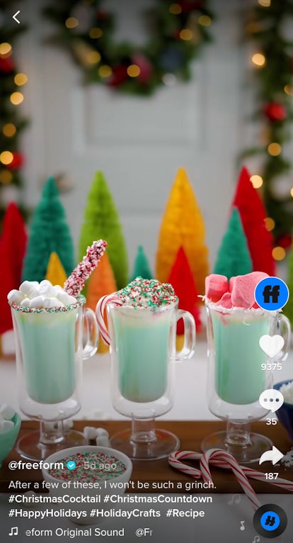 Three green hot chocolate drinks sit on a white board with festive garnishes on top. 