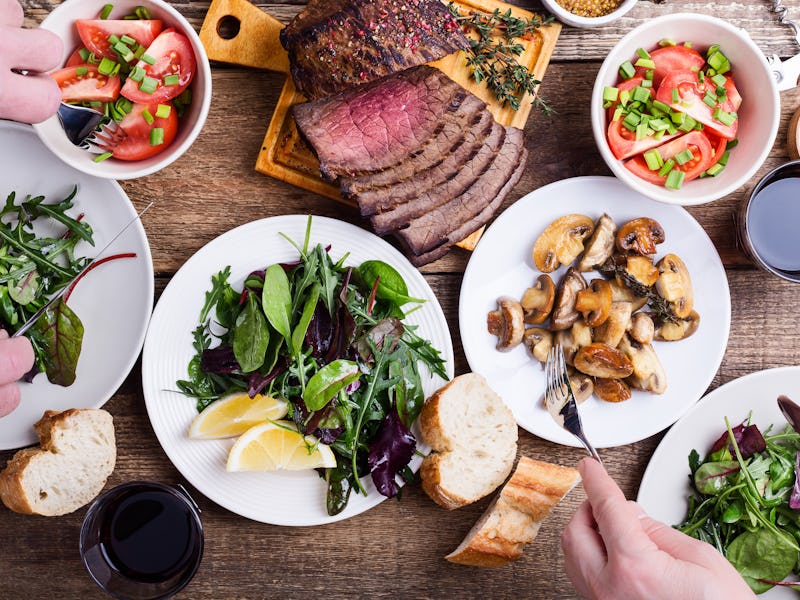 Overhead photo of food on a table, with people taking servings