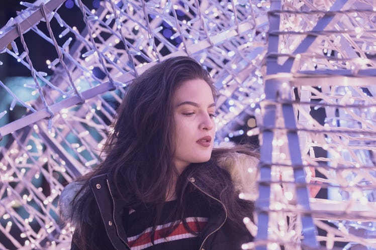 Woman Standing Against Illuminated Christmas Lights At Night
