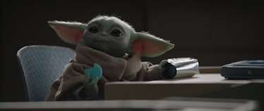 Grogu in The Mandalorian season 3 sitting at a table with a cookie in his hand 