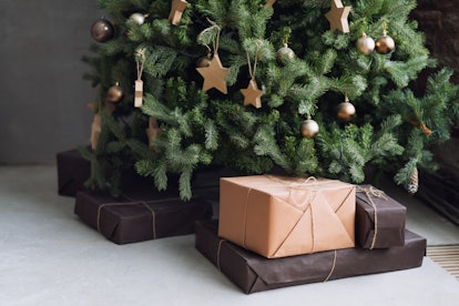 A green christmas tree with presents placed at the bottom wrapped in simple brown wrapping paper
