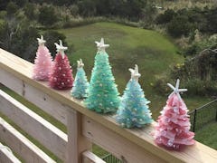 Sea glass Christmas trees line the railing of a back porch overlooking a grassy yard.