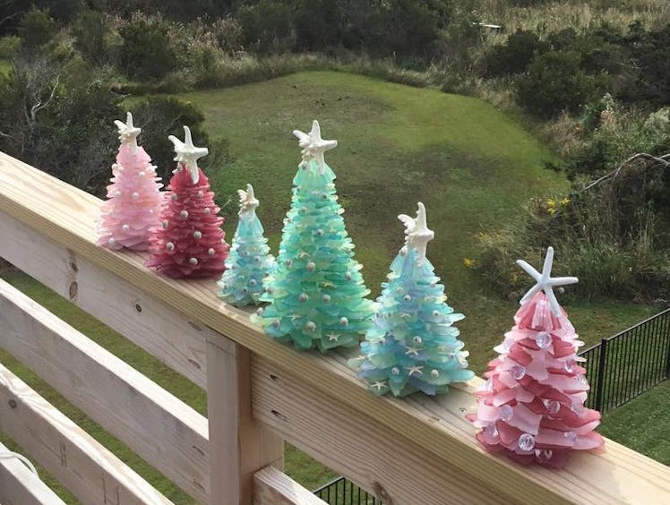 Sea glass Christmas trees line the railing of a back porch overlooking a grassy yard.