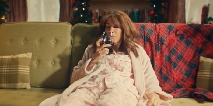 Kristen Wiig slumps on couch in pajamas with a glass of wine.