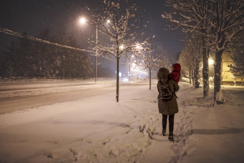 Mother and toddler walking in the snow on a winter's dark morning.