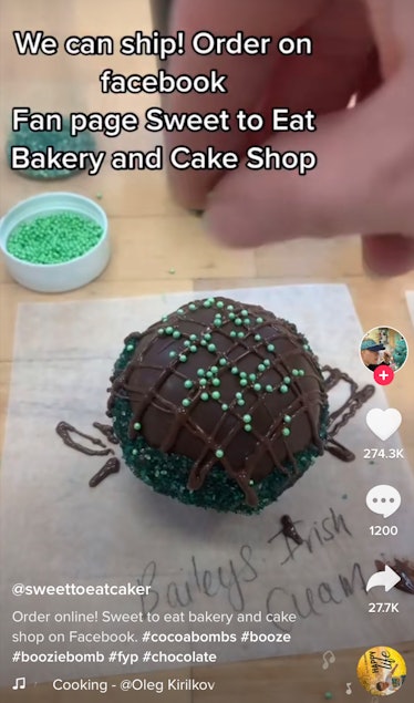 Someone sprinkles green sprinkles on top of a Baileys hot chocolate bomb. 