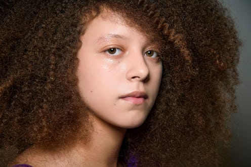 A model with warm chocolate hair styled in small curls