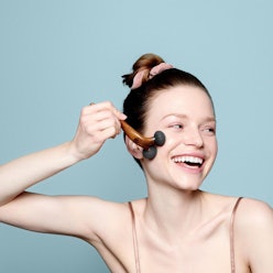 A woman smiling and using the Face Roller by Carbonnique, a skin care tool to fight wrinkles and dul...