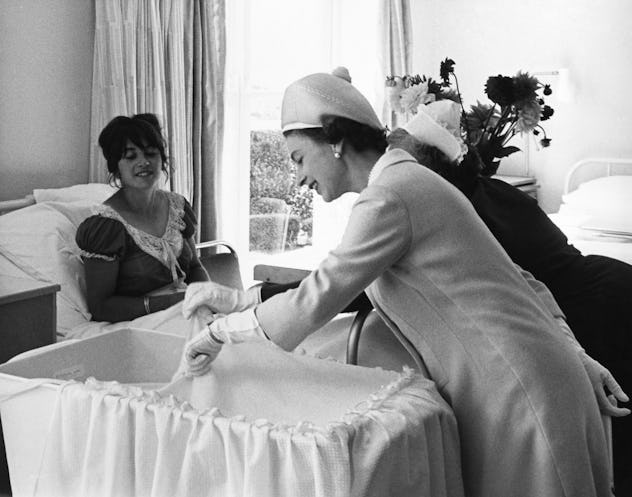 Queen Elizabeth II looking at a baby in the maternity ward.