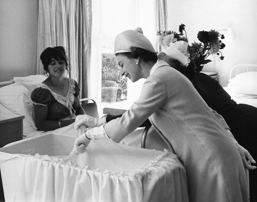 Queen Elizabeth II looking at a baby in the maternity ward.