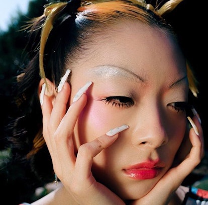 Soji Nails with long white nails looking off into the distance