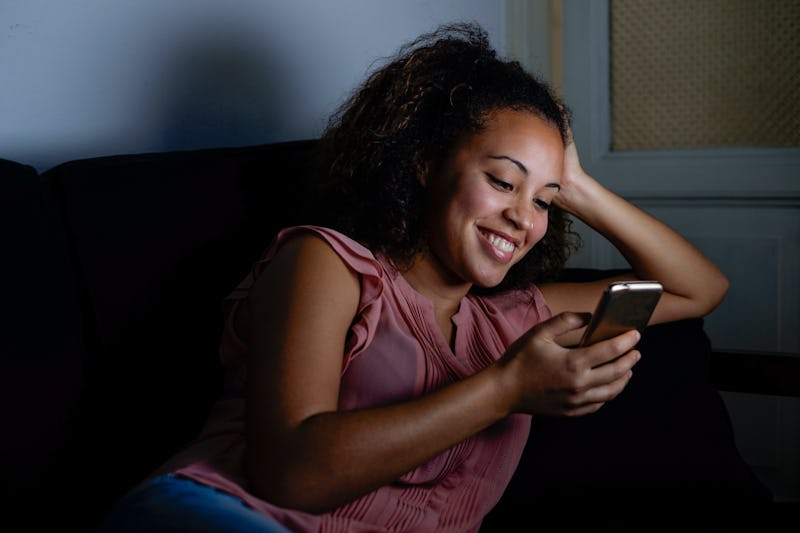 Happy young woman typing on her smart-phone display
