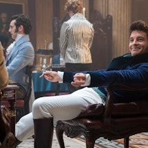 Jonathan Bailey, dressed as Anthony Bridgerton, smoking a cigar while resting on a vintage chair on ...