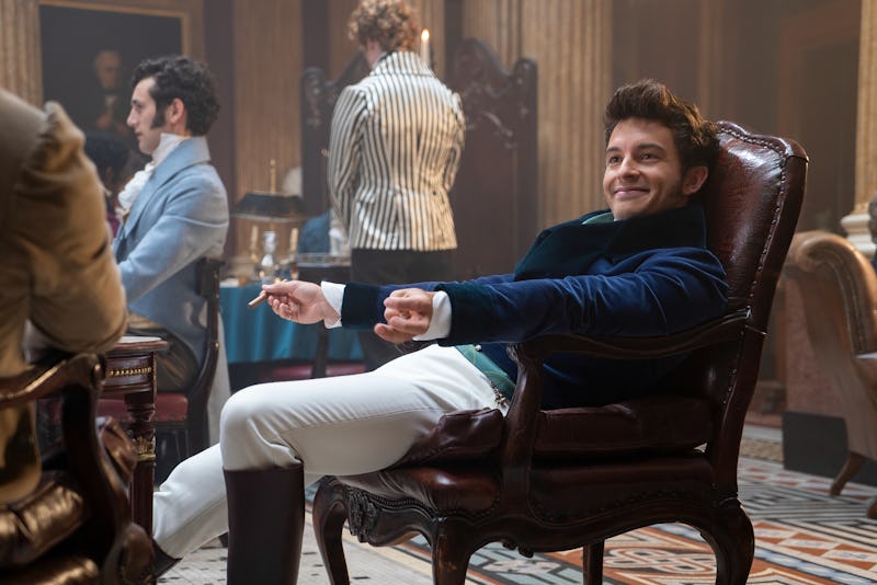 Jonathan Bailey, dressed as Anthony Bridgerton, smoking a cigar while resting on a vintage chair on ...