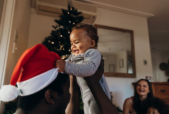 parent holding happy baby in front of a christmas tree