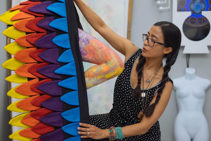 The artist Saya Woolfalk at work in her studio, with a large colorful sculpture.