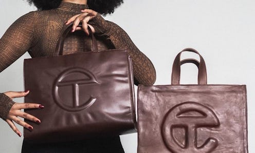 A woman in a brown turtleneck holding up a leather Medium Chocolate Shopping Bag from Telfar