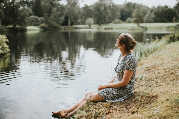 woman in sundress, sitting by a lake