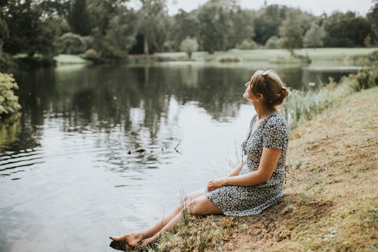 woman in sundress, sitting by a lake