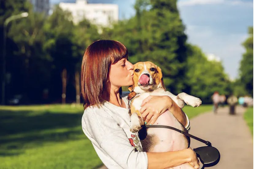 A woman holding and kissing her dog who has separation anxiety