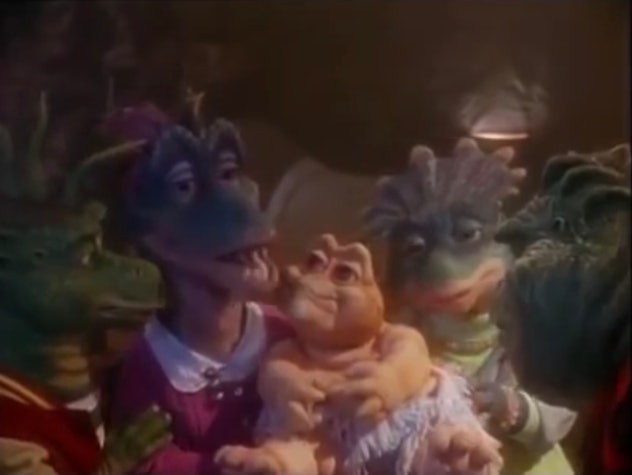 The puppet cast of 'Dinosaurs' gathers around their new baby.