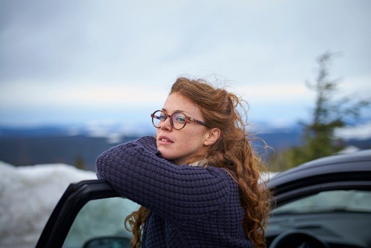 Woman leaning on car in winter