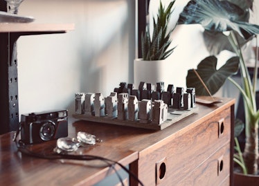 A custom concrete chess set sits on a cabinet next to a camera and glasses, and would be a perfect g...