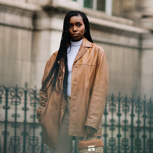 A woman in a caramel winter coat, sweatpants and a caramel purse