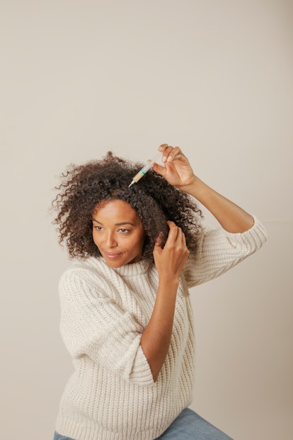 Curly woman applying Harklinikken's Customized Hair Treatment