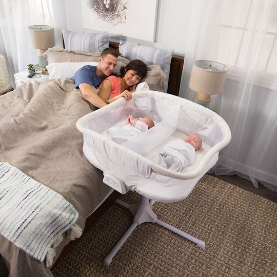Twin babies sleeping in a bassinet next to the bed of their parents